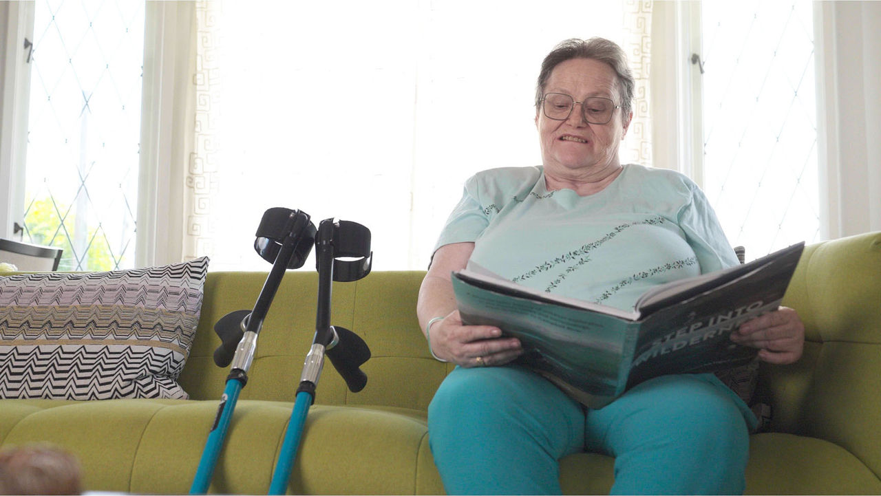 Photo of Linda sitting on the couch, reading